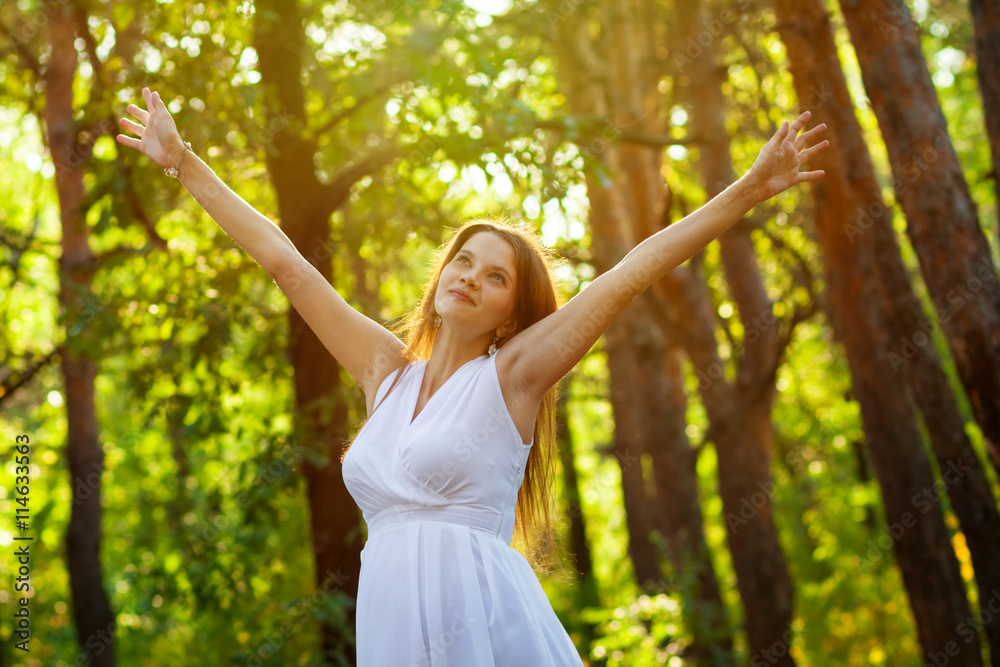 Happy pregnant woman breathing fresh air in the woodland