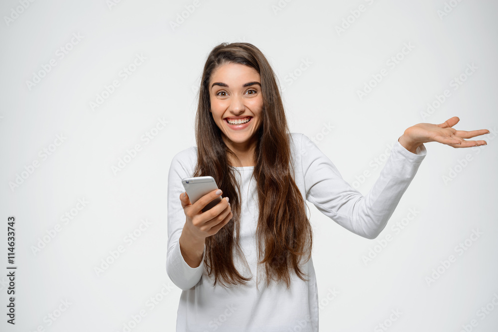 Portrait of young happy girl holding her phone in hand waving over white background Portrait of young happy girl holding her phone in hand waving over white background