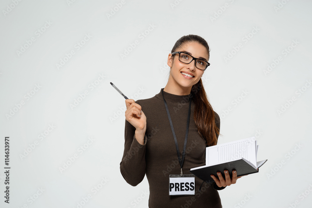 Beautiful young smiling girl writing in notebook. Over white background Beautiful young smiling girl writing in notebook. Over white background