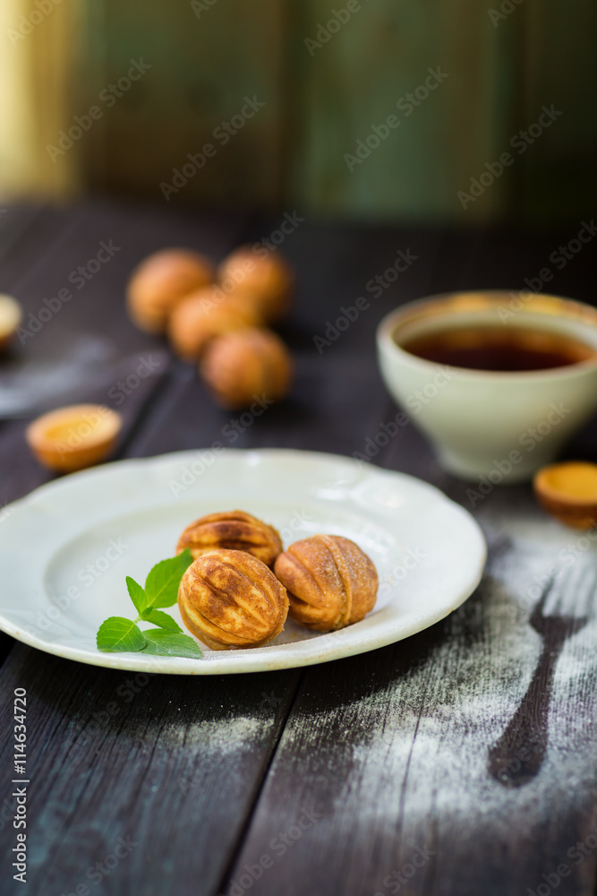 Walnut cookies on a white plate, wooden background