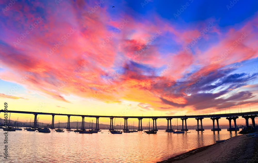 Coronado Island vibrant cloudy sunrise over Coronado Bridge and San Diego Bay.  San Diego, California USA.