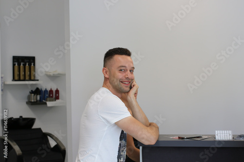 Handsome smiling man at the Hair Salon reception desk