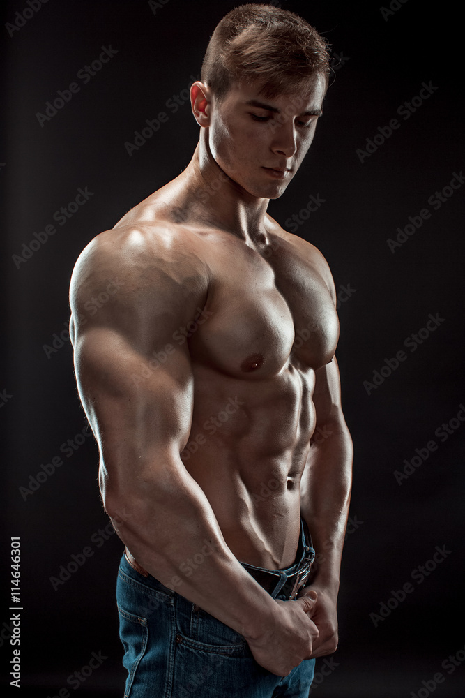 Muscular bodybuilder guy doing posing over black background