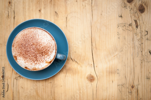 Fresh cup of coffee on a wooden table background in the cafe