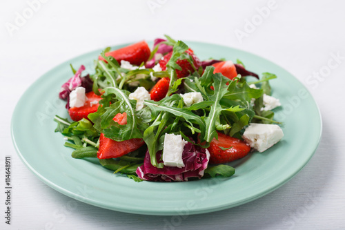 Salad of fresh strawberries,arugula,lettuce with pieces of cheese.selective focus.