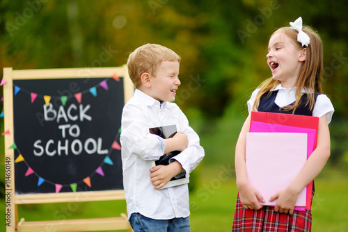 Two adorable little schoolkids feeling excited about going back to school