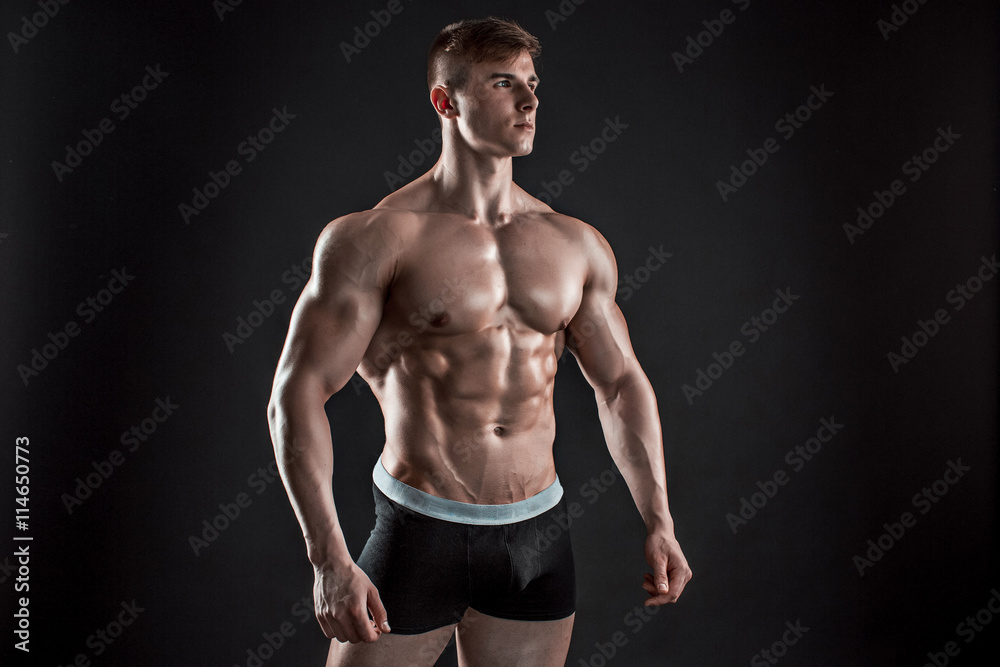 Muscular bodybuilder guy doing posing over black background Muscular bodybuilder guy doing posing over black background