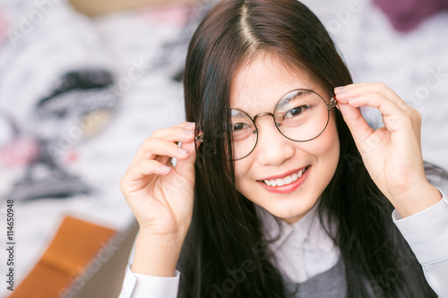 Fototapeta Naklejka Na Ścianę i Meble -  Beautiful asian young curly woman with glasses sitting on the be