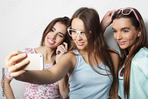 three happy teenage girls with smartphone taking selfie photo