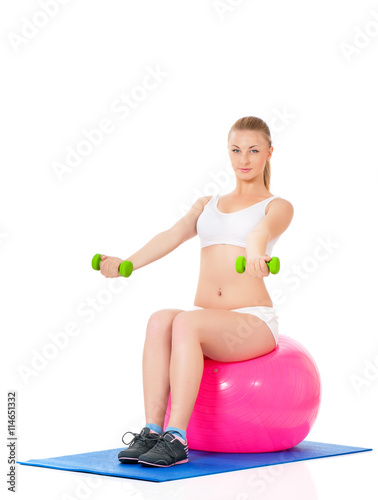 Beautiful young girl doing exercises with fit ball and dumbbells isolated over white background