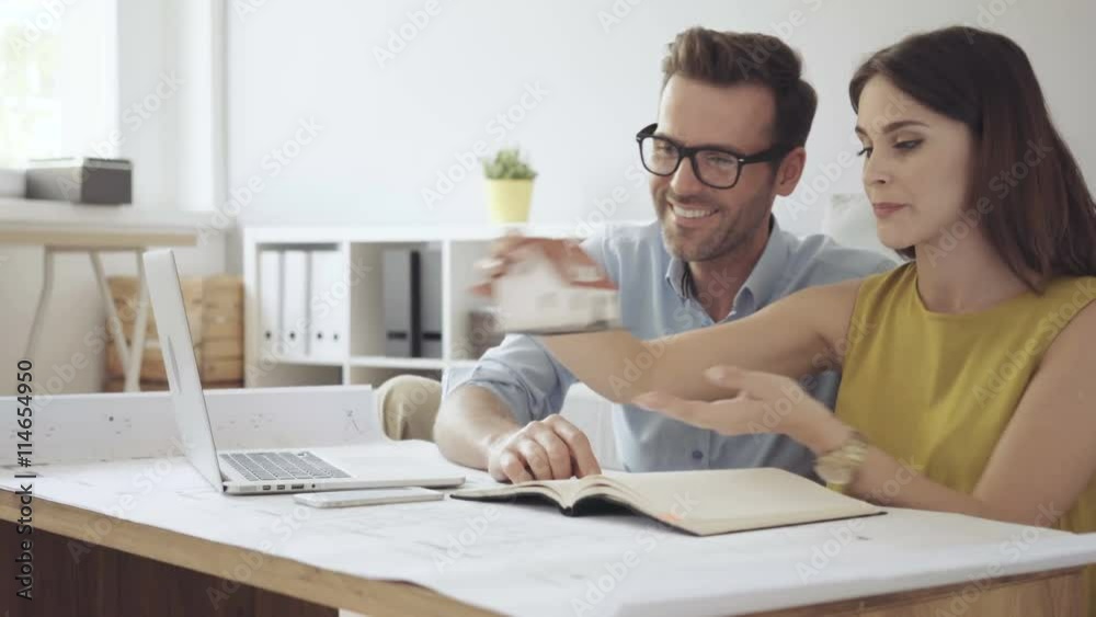 Happy couple planning new home desing working with laptop and blueprints Happy couple planning new home desing working with laptop and blueprints