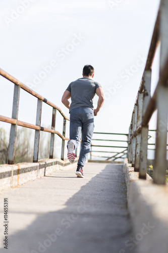 Full length portrait of handsome runner jogging fast down the br