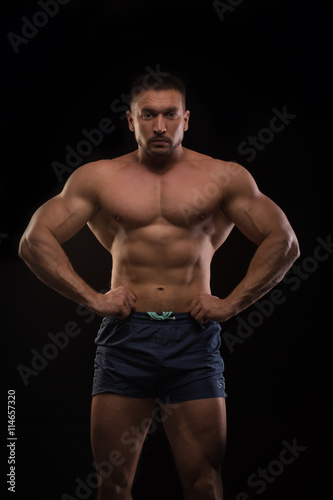 handsome muscular bodybuilder posing on a black background © Rudkov