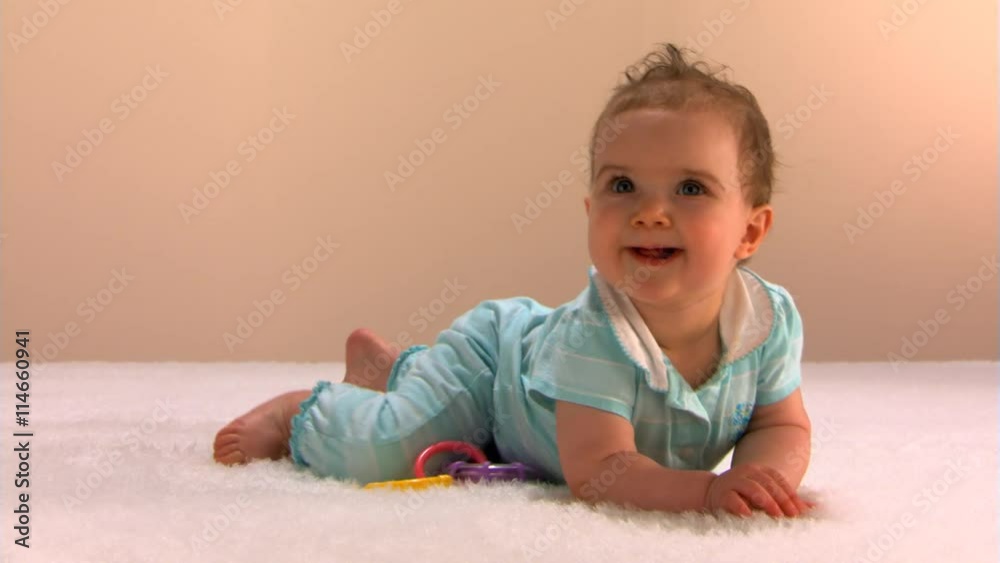 Smiling baby girl rises to hands and knees and crawls toward the left Smiling baby girl rises to hands and knees and crawls toward the left