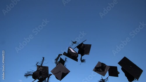 Ultra-slow motion shot of academic caps sailing into blue sky on graduation day