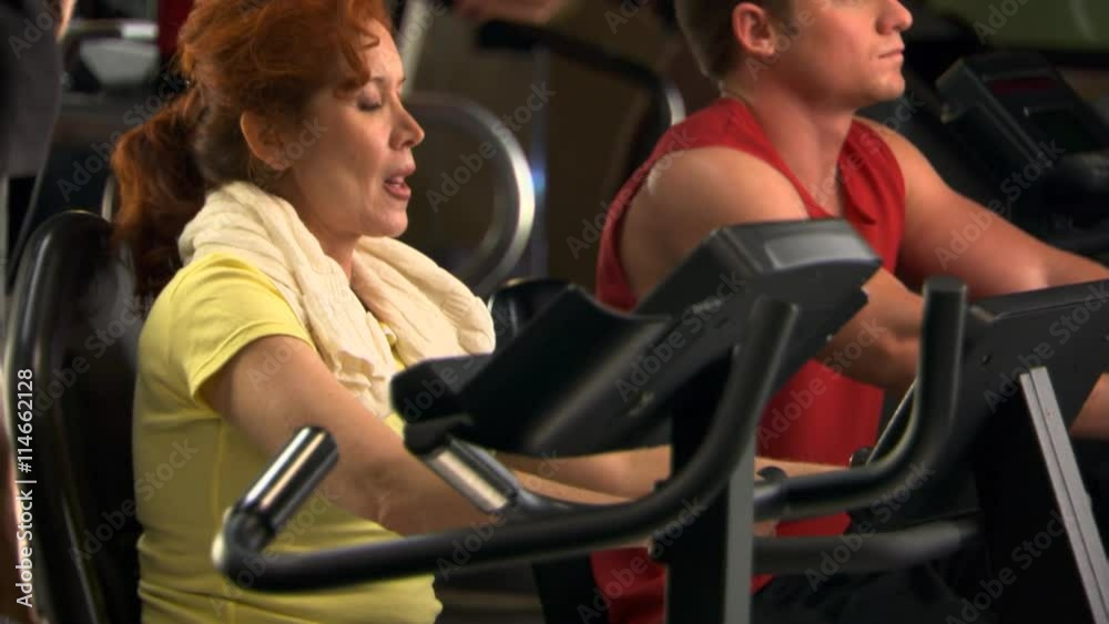 Man and woman pedaling recumbent exercise bikes in fitness club Man and woman pedaling recumbent exercise bikes in fitness club