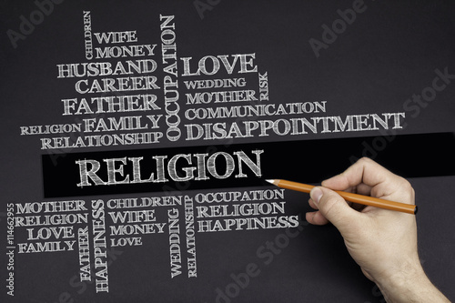 Hand with a white pencil writing: Religion word cloud