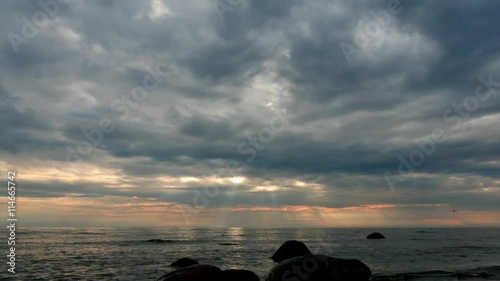 Rain lines afar on horizon time lapse at cloudy sunset in sea photo