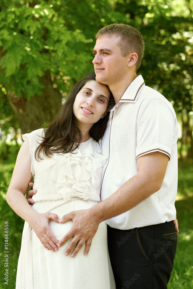 pregnant woman with husband posing in the city park, family port pregnant woman with husband posing in the city park, family port