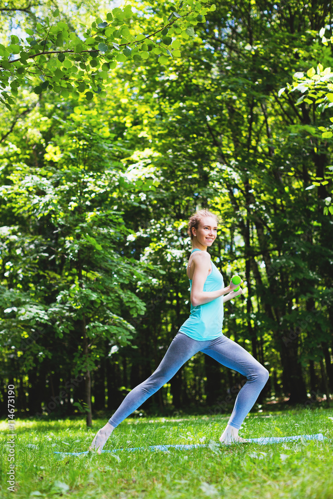 Woman doing exercise with dumbbells in the park. Woman doing exercise with dumbbells in the park.
