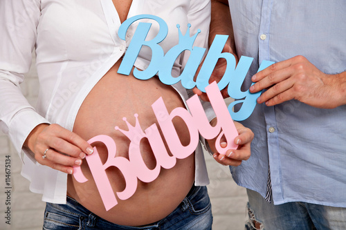 pregnant woman's belly. Mom and Dad hands holding two bear. twins.