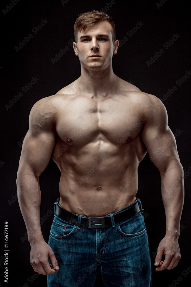 Fototapeta premium Muscular bodybuilder guy doing posing over black background