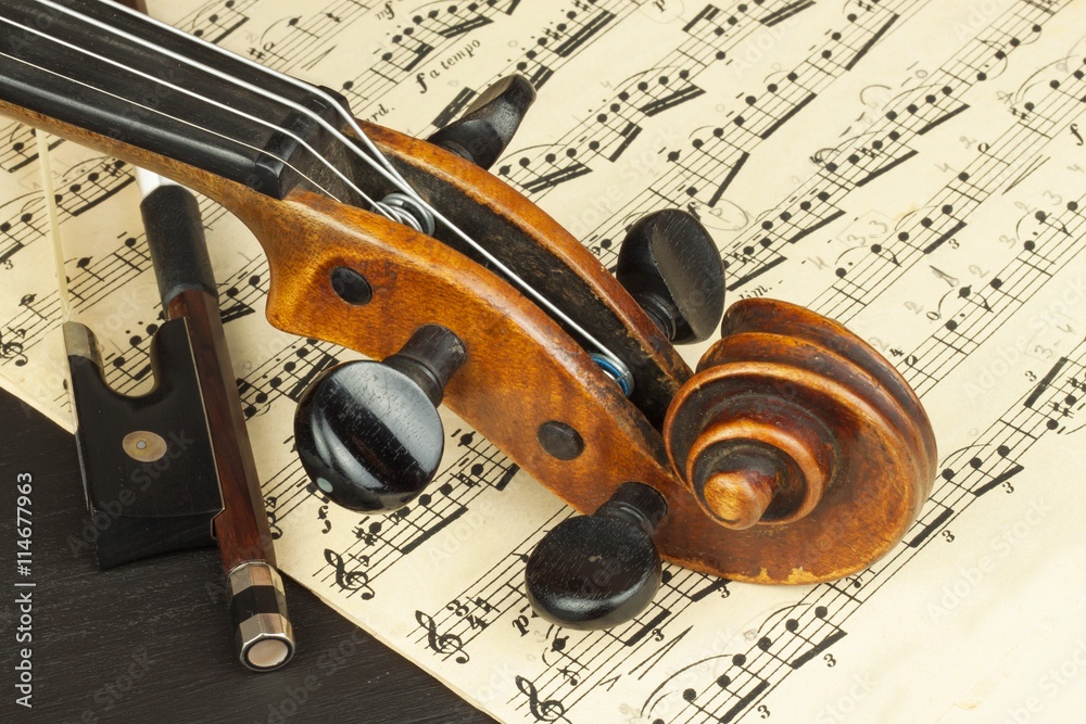 Naklejka premium Old violin on dark wooden table. Detail of old violin on a black background. Invitation to the Violin Concerto.