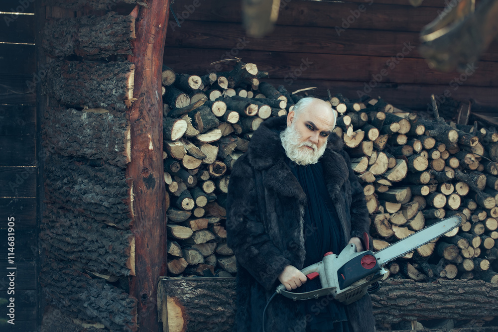 Fototapeta premium Old bearded man with chainsaw
