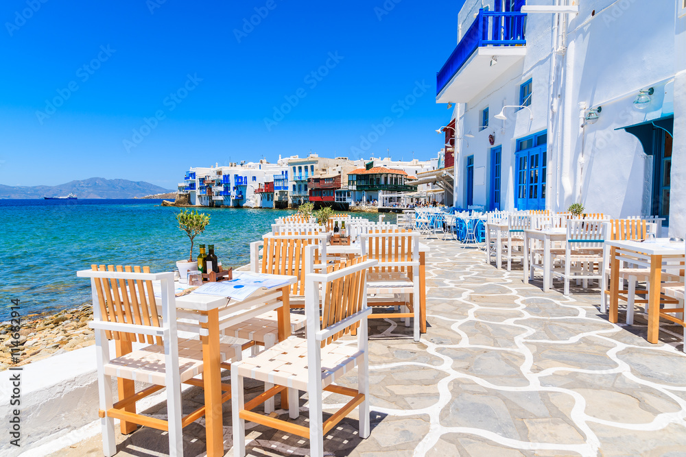 Naklejka premium Krzesła z stołami w typowej greckiej tawernie w Małej Wenecji części miasta Mykonos, wyspa Mykonos, Grecja