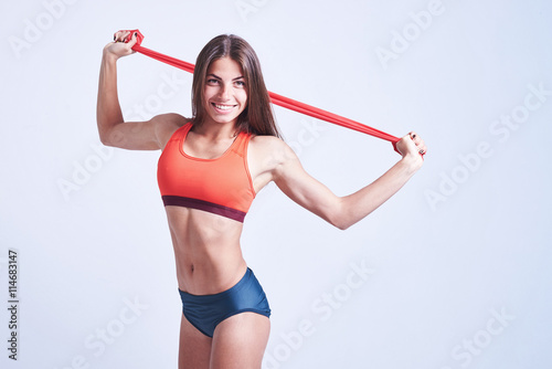 Woman working out with band in fitness gym isolated over white