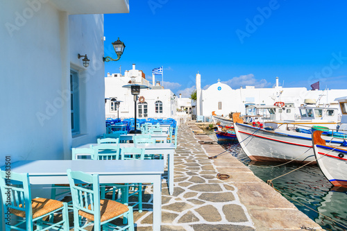Taverna tables and typical Greek fishing boats in Naoussa port, Paros island, Cyclades, Greece