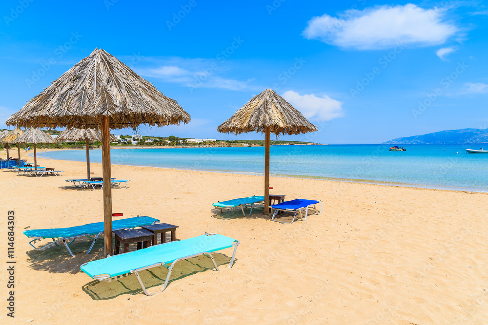 Umbrellas with sunbeds on beautiful sandy Santa Maria beach with turquoise sea water, Paros island, Greece