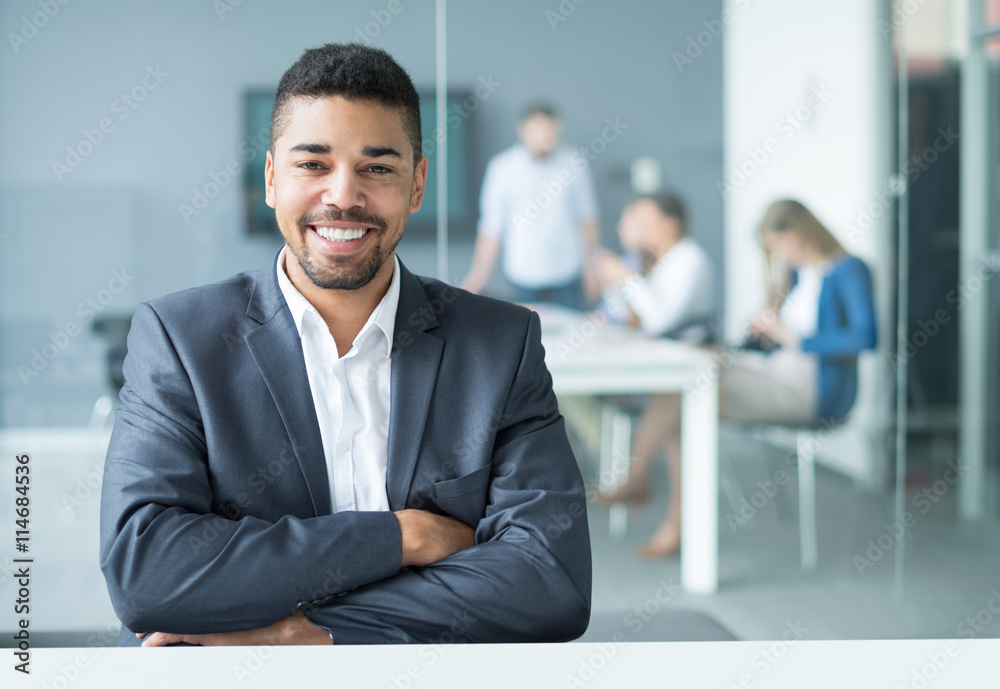 Smiling young businessman sitting in office Smiling young businessman sitting in office