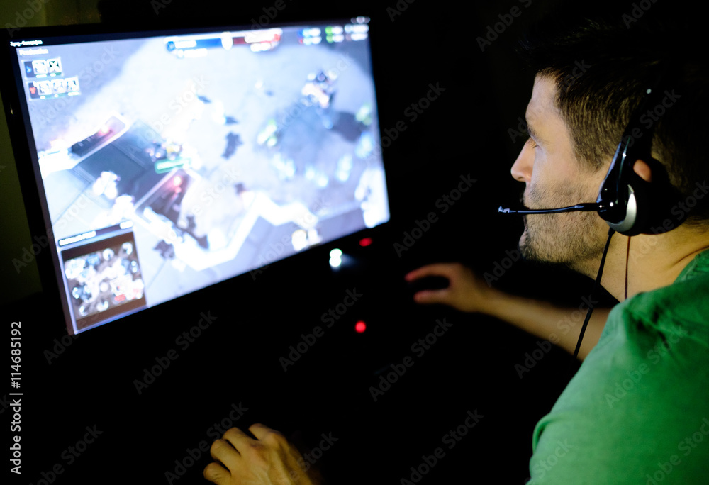 Man playing video game in dark room StockFoto Adobe Stock