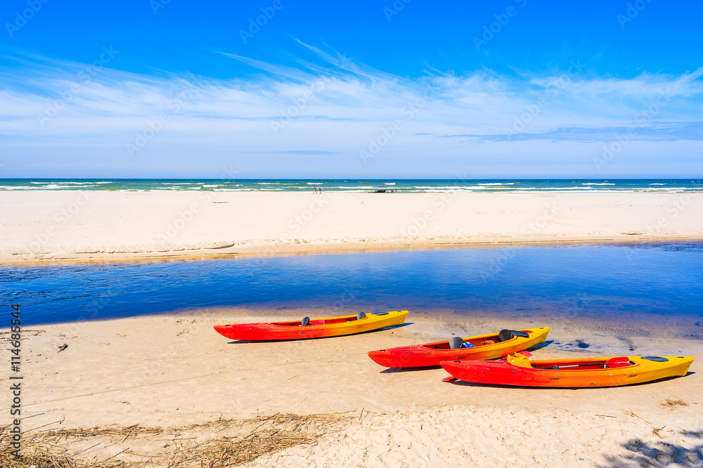 Kayaks on white sand beach in Debki village where Plasnica river has its estuary to Baltic Sea, Poland Kayaks on white sand beach in Debki village where Plasnica river has its estuary to Baltic Sea, Poland