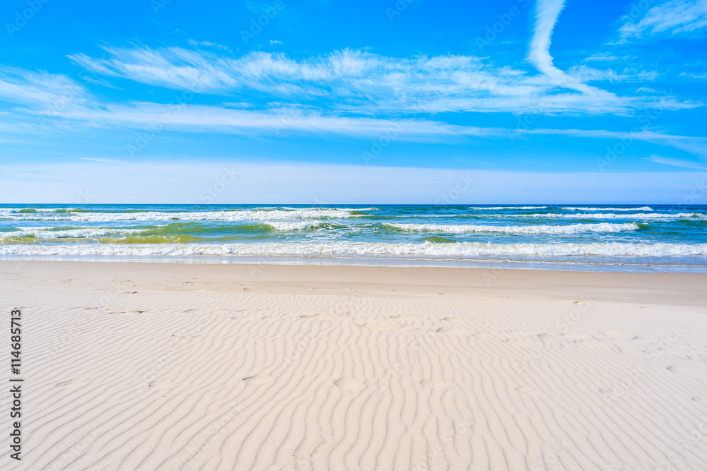 A view of white sand beach and waves on blue Baltic Sea, Bialogora coastal village, Poland