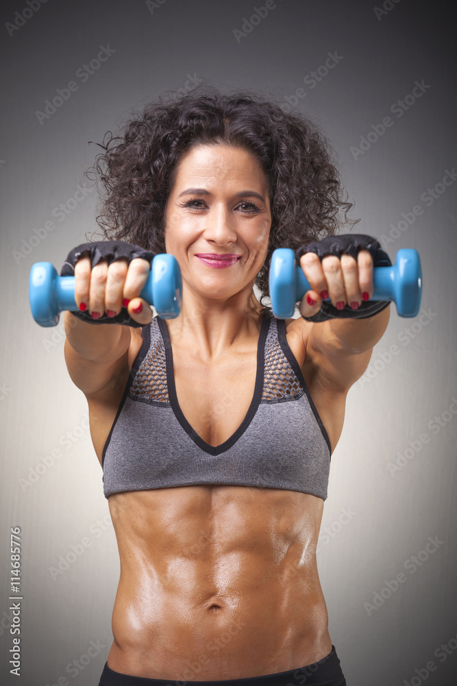 Fit woman lifting weights on grey bakground Fit woman lifting weights on grey bakground