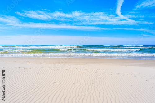 A view of white sand beach and waves on blue Baltic Sea, Bialogora coastal village, Poland