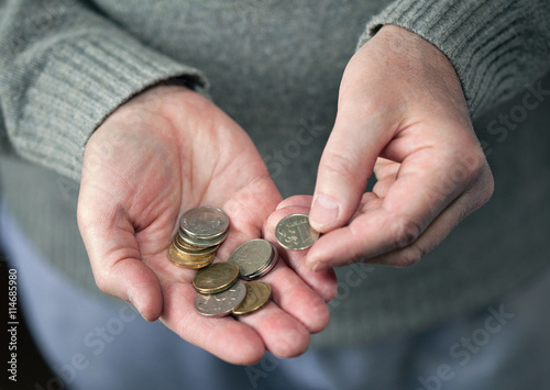 An elderly man counts coins