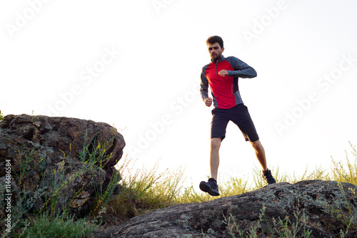Young Sportsman Running on the Rocky Mountain Trai in the Evening. Active Lifestyle