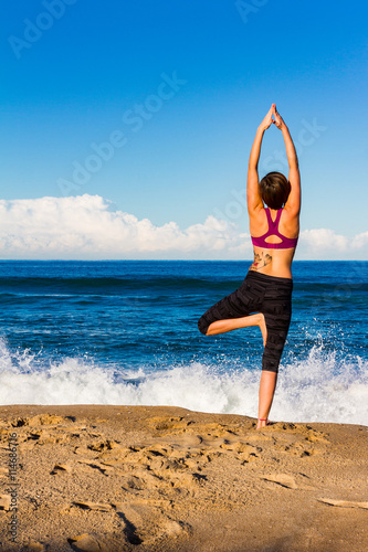 Young woman makes Yoga on a Beach with waves in Background