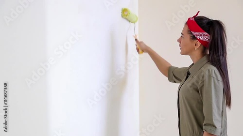 Girl paints a wall roller white.