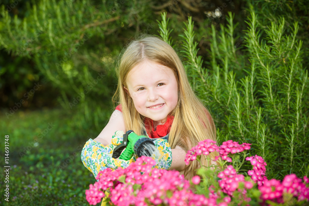 Beautiful blond girl watering flowers, lawn on a sunny beautiful Beautiful blond girl watering flowers, lawn on a sunny beautiful