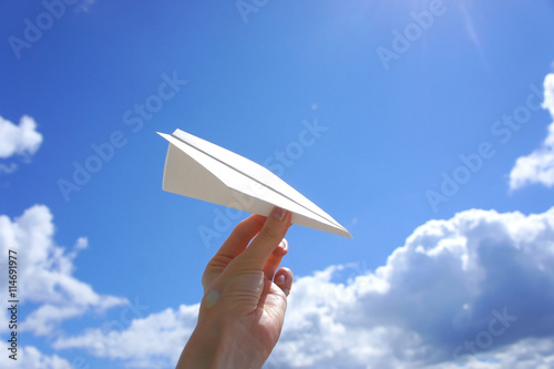 Hand with paper plane on a background of clouds