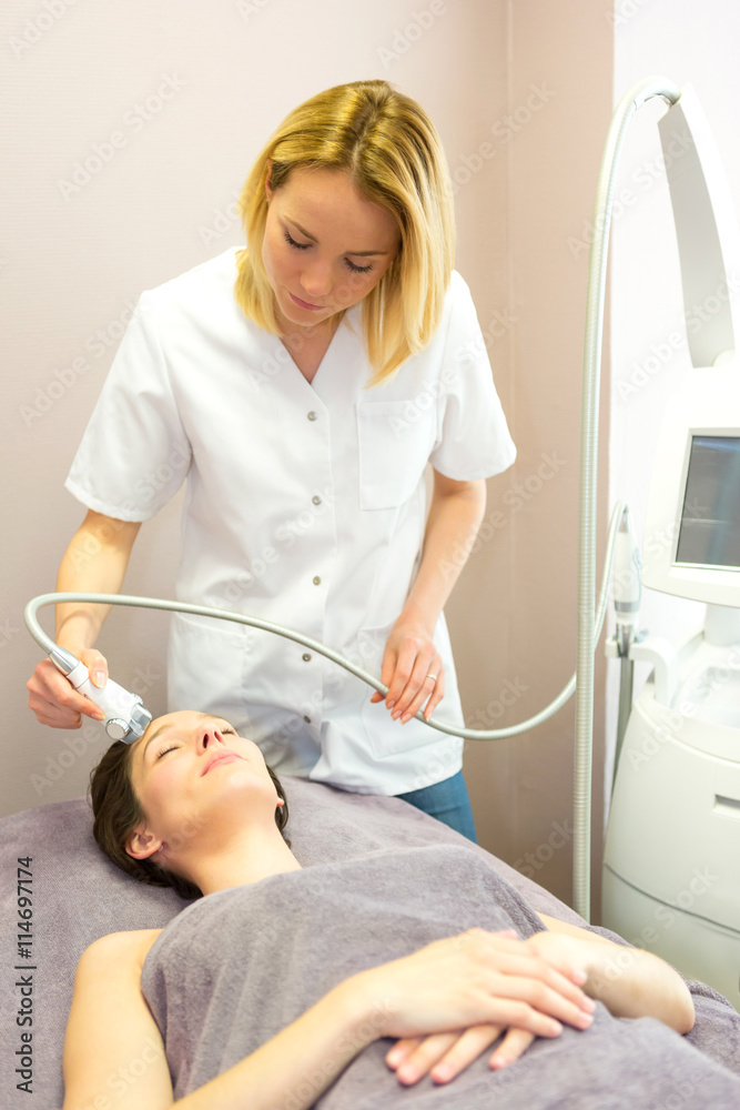 Fototapeta premium Young attractive blond beautician woman doing a facial massage t