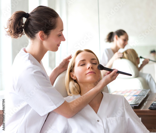 Two young beautician students working during make up classes