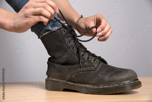 Woman's hand lacing up a black leather boot