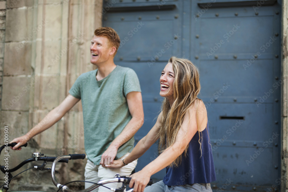 Portrait of laughing woman with bicycle holding hand with her boyfriend in the background Portrait of laughing woman with bicycle holding hand with her boyfriend in the background