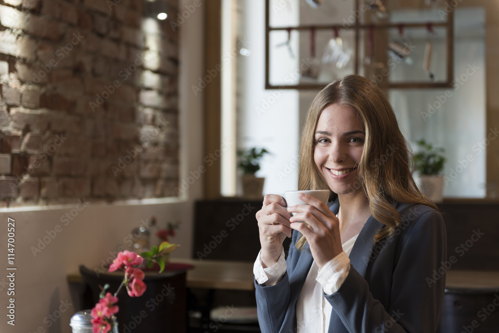 Portrait of smiling young woman drinking coffee in a coffee shop Portrait of smiling young woman drinking coffee in a coffee shop