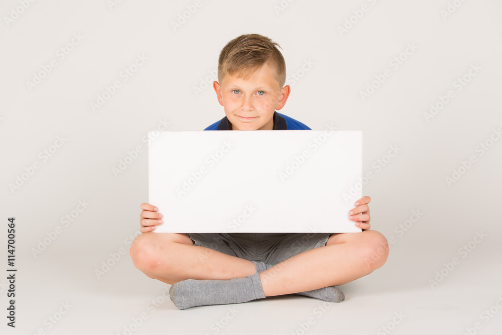 junger Mann in kurzen Hosen / Freizeit Outfit hält weißes Schild mit Platz für Text junger Mann in kurzen Hosen / Freizeit Outfit hält weißes Schild mit Platz für Text